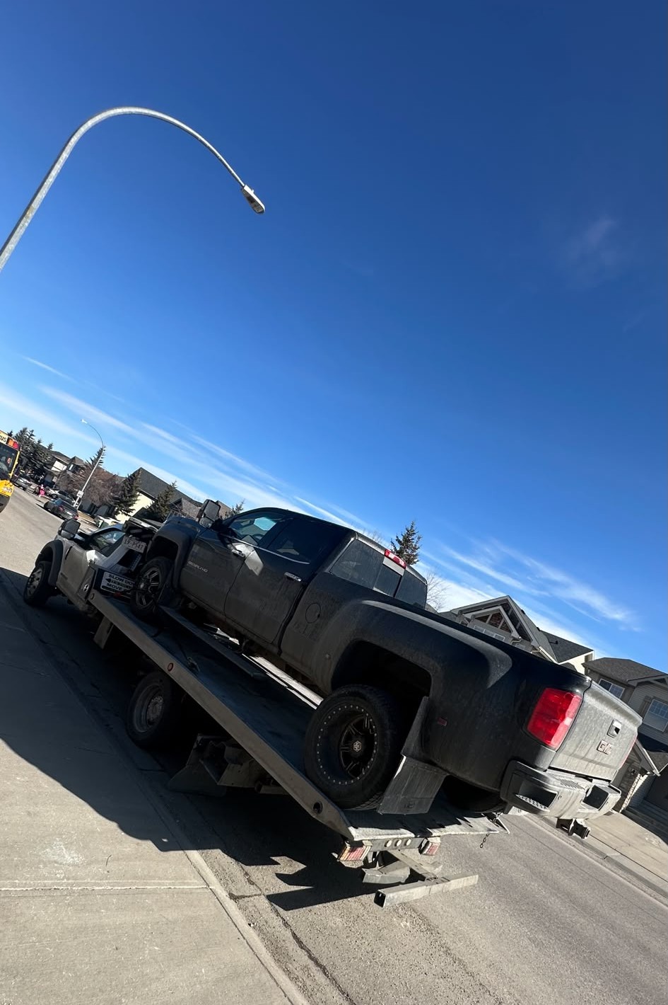 AR Towing flatbed truck hauling a pickup past a Calgary neighborhood