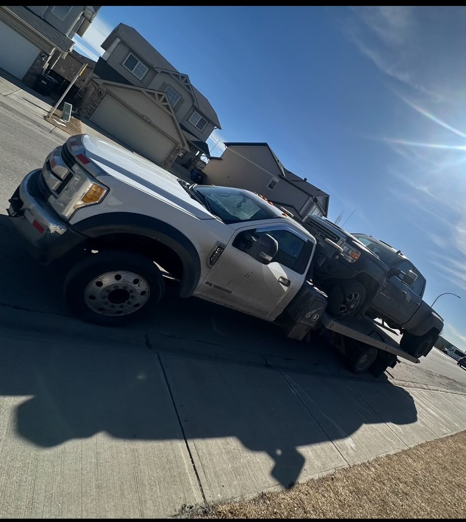 AR Towing flatbed truck loaded with a pickup in a Calgary driveway